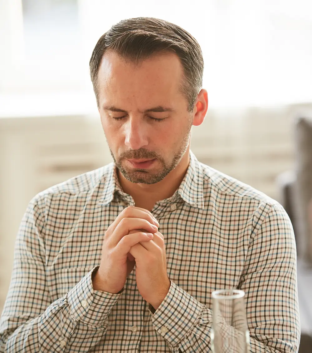 Man praying with closed eyes during a Christian counseling session