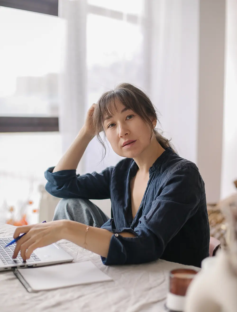 Woman sitting at a desk with a laptop, looking forward gently to show the comfort of seeking individual counseling help